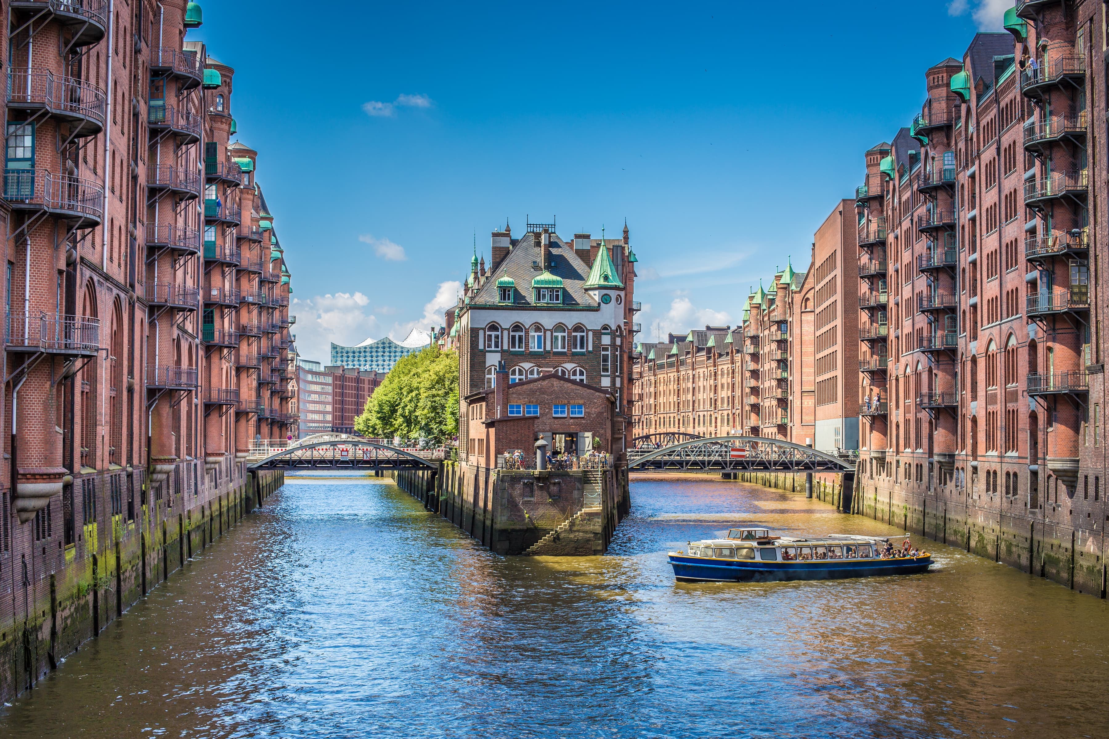 Speicherstadt Hamburg mit Fleet, historischen Backsteinbauten und Ausflugsboot bei Sonnenschein