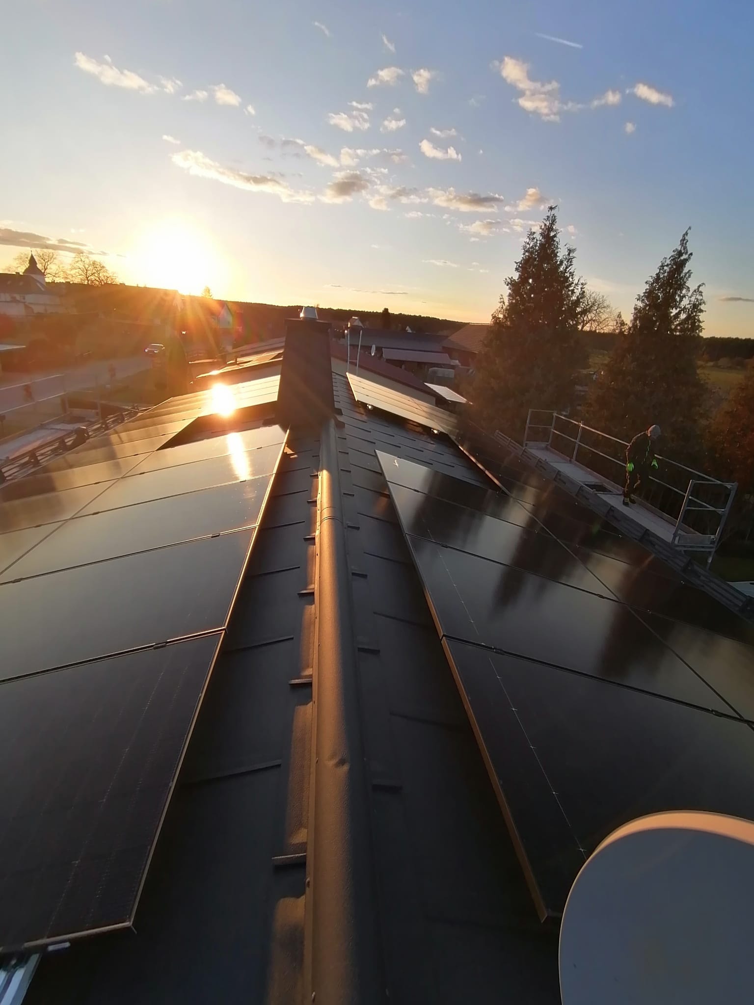 Photovoltaikanlage auf Hausdach im Sonnenuntergang mit Monteur bei der Solar-Installation